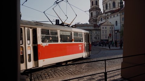 two old red trams passing through square in Prague