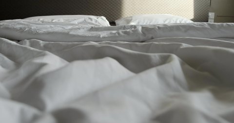 Crumpled messy white blanket untidy with two pillow, Unmade bed after waking up in the morning with a duvet on the bed.