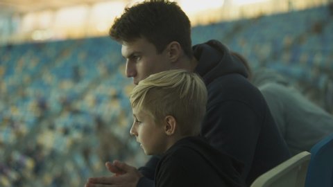 Two brothers watching football at stadium, spending time together, fellowship