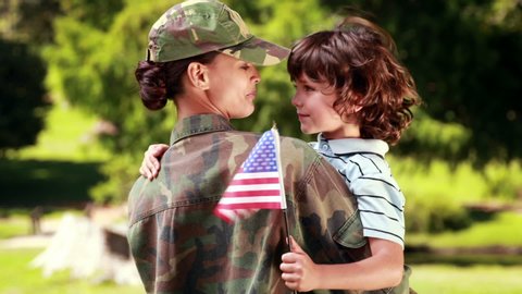 Animation of a house shape made of cloud floating with a Caucasian soldier woman holding her son with an American flag in the background