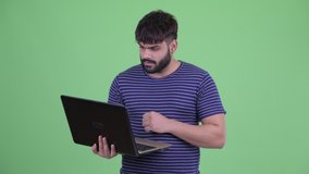 Angry young overweight bearded Indian man video calling with laptop