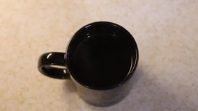 Slow-motion clip of steam rising from black coffee mug from the top. Filmed in 60fps, slowed 1/2 and exported in 24fps.