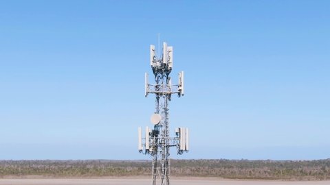 Aerial Orbit: Footage of 5G towers with blue sky background and thin horizon. Rural broadband in country towns. Space for Copy.