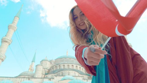 Slow Motion: Attractive beautiful girl in shirt waves Turkish flag with view of Sultan Ahmet Mosque in Istanbul,Turkey.Travel Concept