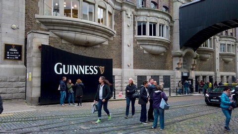 Dublin / Ireland - 06 15 2019: Tourists meeting at the entrance of Guinness storehouse while taxi driving by.