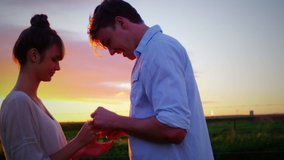 Animation of a side view of a young Caucasian man proposing to a young Caucasian woman at sunset, seen on a screen of a smartphone in picture mode with icons in the foreground - Powered by Shutterstock - Get 15% off with code: PIKWIZARD15