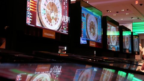 COQUITLAM , British Columbia / Canada - 05 31 2019: Coquitlam, BC, Canada - May 31, 2019 : Motion of people playing casino roulette on machine with reflection spinning ball on screen inside Casino