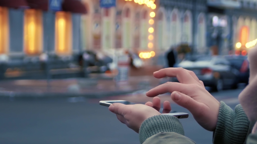 Female hands on the street interact with a HUD hologram with cup of coffee. Woman uses the holographic technology of the future in the smartphone screen on the background of the evening city Royalty-Free Stock Footage #1036406390