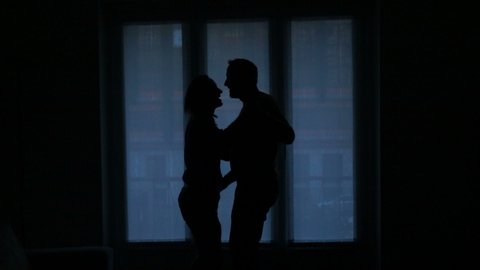 Young couple dancing at home by window, slow motion shot