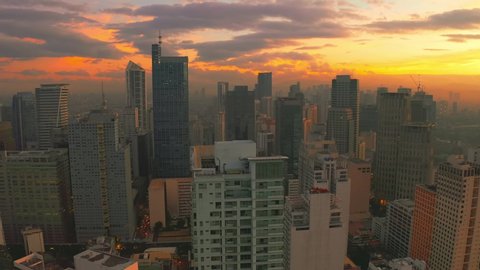 Sunrise in a downtown view from high above with multiple skyscrapers in Manila city, Philippines. Aerial 4K