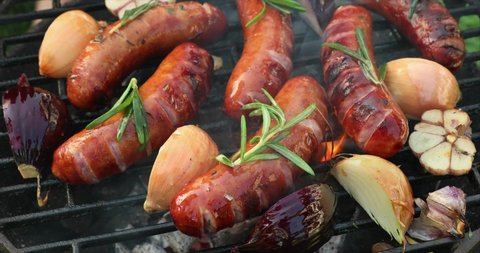Grilling sausages with the addition of herbs and vegetables on the grill plate, close-up, 4k. Grilling food, bbq, barbecue