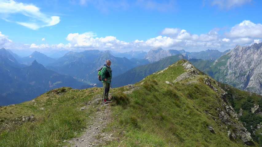 Happiness man hiker, tourist traveler walking on the top of mountain in summer sunny day under sun light. Beautiful mountains landscape view.