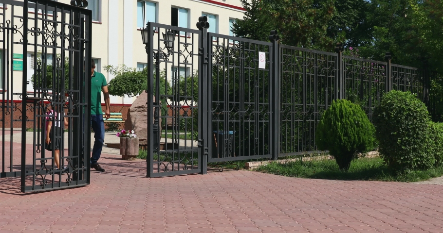 Father taking her cute little daughter out of school after lessons on sunny day