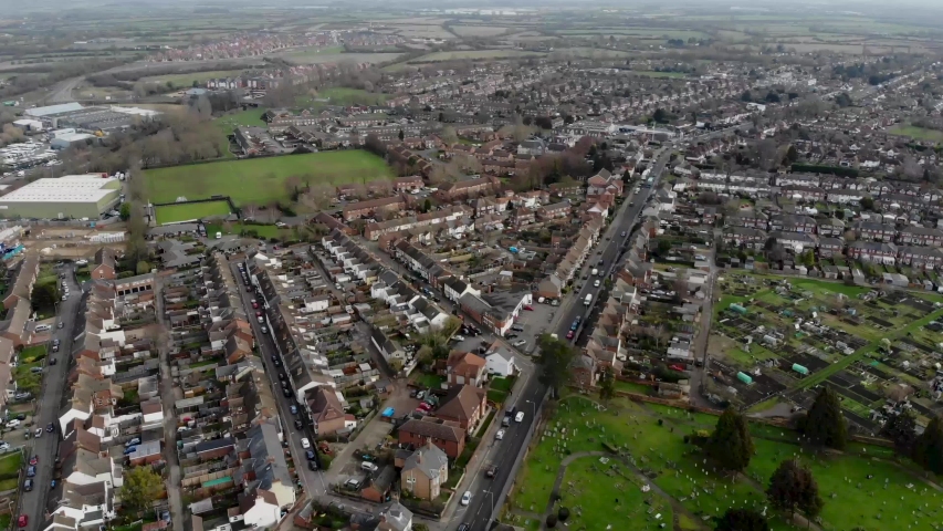 Aerial footage of the town of Aylesbury in the UK showing typical British roads, residential properties, rows of houses and businesses with a busu main road with traffic.