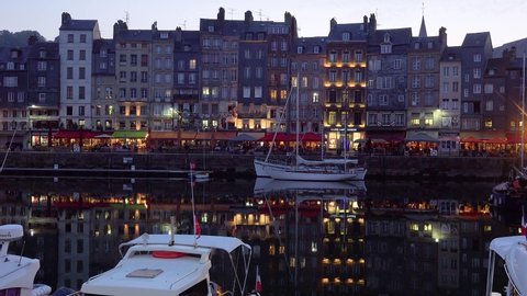 HONFLEUR, FRANCE - CIRCA 2018 - Night establishing of Honfleur France with old colorful buildings, yachts sailboats in harbor and cafes.
