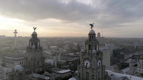 Liverpool / United Kingdom (UK) - 08 04 2019: Sunrise over Liverpool liver building, Liverpool skyline radio tower & cathedrals along the horizon. Stunning aerial orbit right.