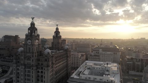 Liverpool / United Kingdom (UK) - 08 04 2019: Sunrise over Liverpool liver building, Liverpool skyline radio tower & cathedrals along the horizon. Aerial orbit left.