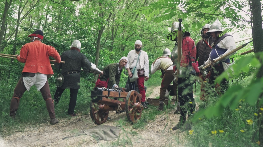 Warriors preparing to the attack and the artilleryist shoot from the cannon on the forest trail.