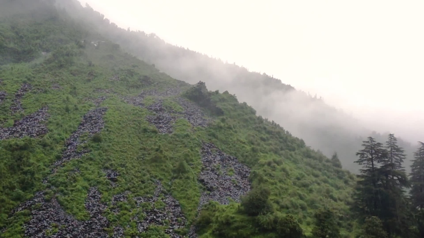 Green plant covered hill with rain falling and a cloud going over the peak in McLeodganj Dharamshala. The multiple treks like Triund, Bhagsu Falls, McLeo in the hill station towns like Shimla | Shutterstock HD Video #1036449293