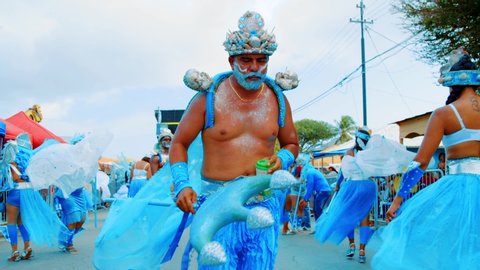 Willemstad / Curaçao - 03 03 2019: A man in a blue merman costume playfully dances toward the camera pointing his trident during the Carnival Gran Marcha in Curacao.