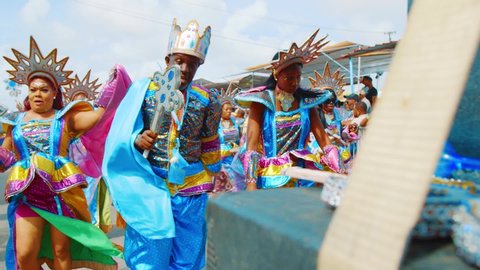 Willemstad / Curaçao - 03 03 2019: People in colorful costumes with crowns and scepters march behind a float in the Gran Marcha of the Curacao Carnival, SLOW MOTION.
