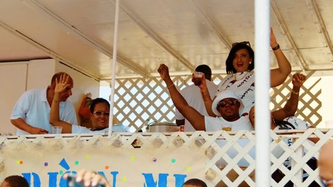 Willemstad / Curaçao - 03 03 2019: People in white relax and wave from a booth in the Gran Marcha of the Curacao Carnival, Slow Motion.