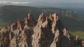 Aerial view of a drone flying over sharp rocky outcrops at sunset. Sharp steep mountain of rock formations for extreme mountaineering. Flight over travel video