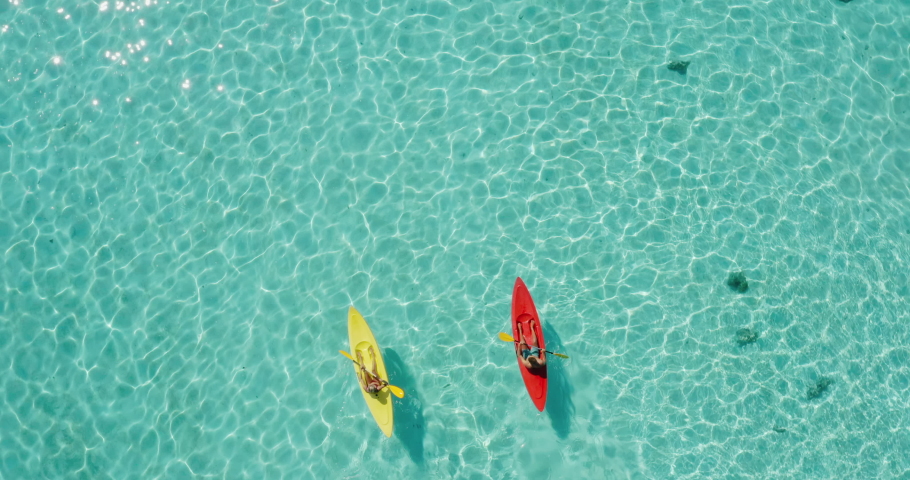 Aerial view of adventurous couple ocean kayaking together in pristine blue lagoon with sunny light textures refracting on the water surface, leisure kayaking tourism