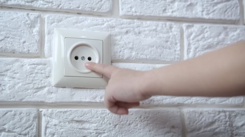 A child touches an electrical outlet. The parent removes the child’s hand from the electrical outlet and protects it from children.
