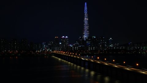 Camera Zoom out on Seoul night lights timelapse of Lotte Tower, Han river, cars,ing along the Jamsil Railroad bridge