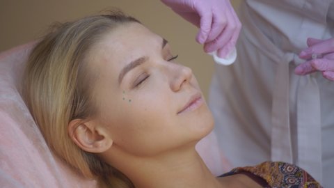 Professional beautician making face injection in a female skin. A woman gets beauty facial cosmetology procedure.