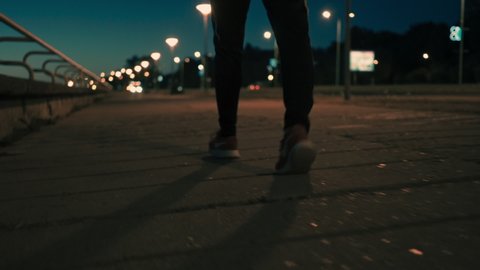 Tallinn / Estonia - 08 06 2019: Sporty Man with sneackers walking in a illuminated road. Runner shoes walk in modern city, night time with artificial illumination.