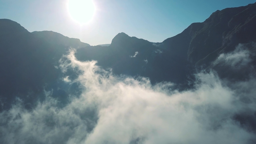 Flying Away from Mountain Above The Clouds with Blue Sky Background