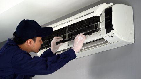 technician service placing back clean filter into air conditioner