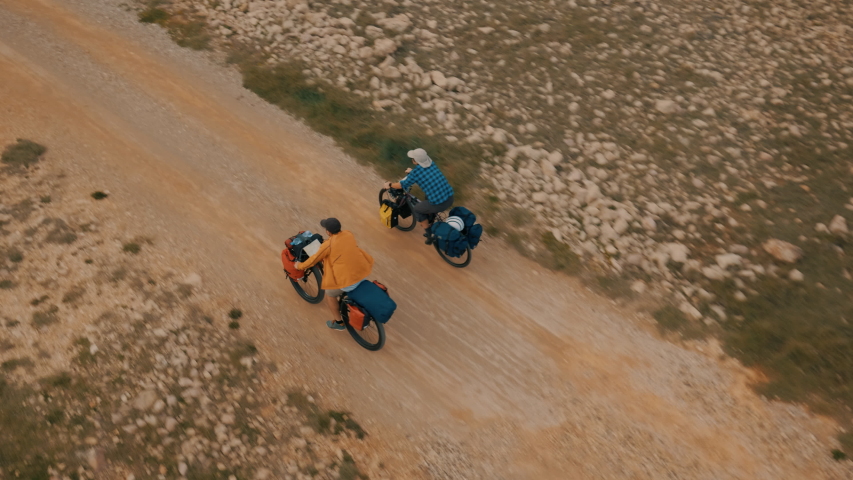 Aerial shot of two guys riding bicycles next to the sea