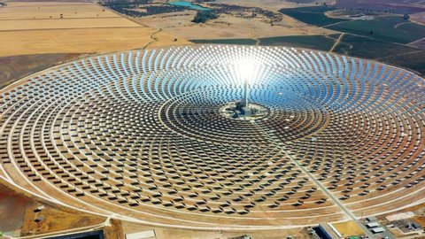 Aerial view of a large solar thermal plant uses mirrors that focus the sun's rays on a collection tower to produce renewable and pollution-free energy.