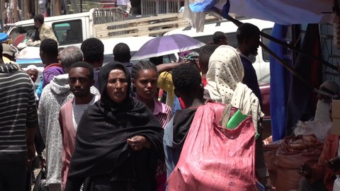 ADDIS ABABA, ETHIOPIA – MARCH 2019: Slow motion of Muslim woman wearing headscarf walking through busy shopping street at market in suburbs of Addis Ababa, Ethiopia