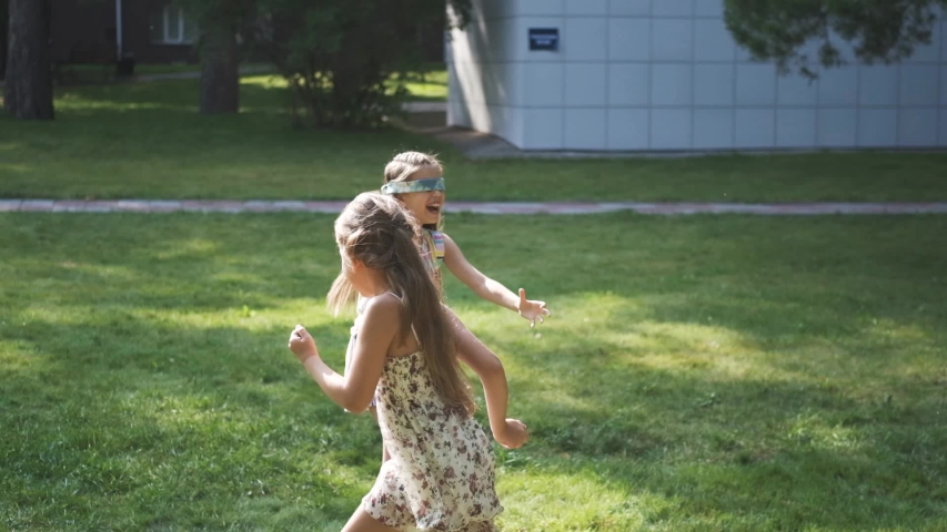 carefree children playing in summer park. blindfolded girl catches her friends