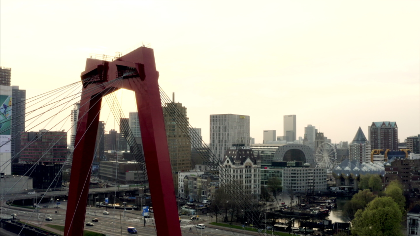 The red bridge in Rotterdam at sunset. The drone is sinking and then rising alongside the architecture of the famous bridge.