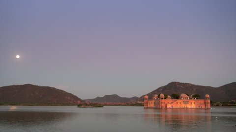 dusk clip of the moon rising and a floodlit jal mahal palace in jaipur, india