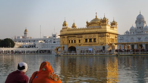 close view of two sikh worshipers sitting beside the sacred pool at golden temple in amritsar, india- 4K 60p