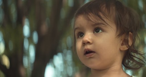 Cute baby girl exploring a park in summer. Real life, candid 4K footage. Anamorphic bokeh.