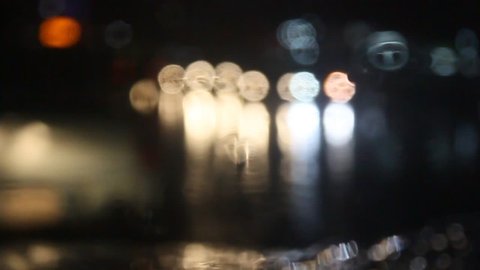 Rain water drops Falling Down On the Windscreen in slow motion, Rain Drops On The Windows Glass, Defocused Night City Traffic Lights.