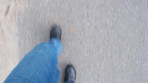 POV looking down at male legs in jeans and boots walking from pavement to grass and back - fast forward walk