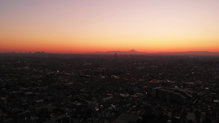 The skies over Tokyo burning orange moments after the sunset, Mt. Fuji is visible on the right and central Tokyo Skyscrapers visible on the left.