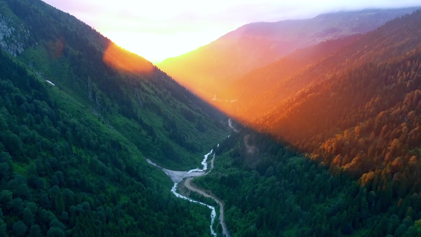 Red colors of sunrise in valley. True color tones, no color correction. Daybreak colors among the mountains. A new day begins in mountainous terrain. Fresh air and a happy morning. 4K Aerial drone.