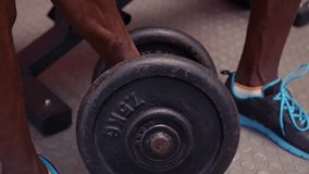 Video of concentrated fit man holding dumbbell in fitness center