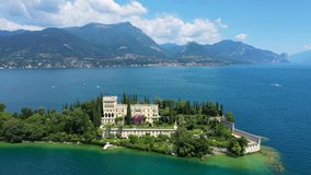 Unique view of the island of Garda. In the background is the Alps. Resort place on Lake Garda north of Italy. Aerial video with drone. Isola del Garda.