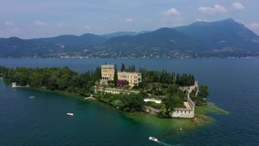 Unique view of the island of Garda. In the background is the Alps. Resort place on Lake Garda north of Italy. Aerial video with drone. Isola del Garda.