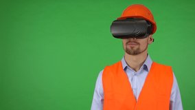 A young construction worker uses VR glasses - green screen studio - he manipulates virtual objects